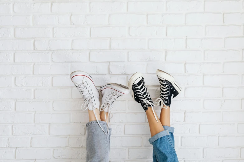 two people standing in front of a white brick wall, trending on pexels, duck shoes, background image, teenage girl, on a white table