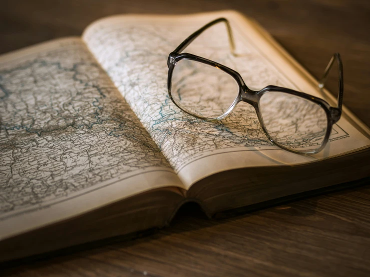 a book with a pair of glasses on top of it, map, black rimmed glasses, thumbnail, brown