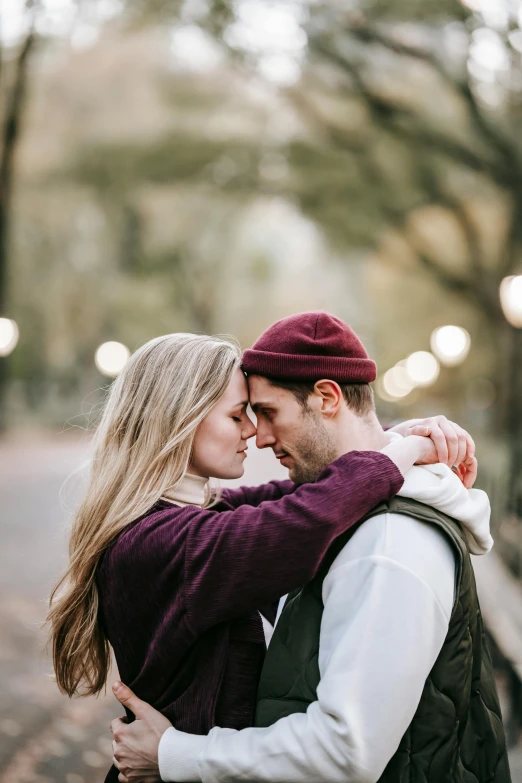 a couple standing next to each other in a park, trending on pexels, romanticism, beanie, soft lights, embracing, profile pic