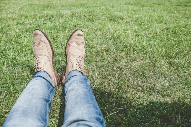 a person sitting on top of a lush green field, trending on pexels, tight blue jeans and cool shoes, wearing a brown, people resting on the grass, androgynous person