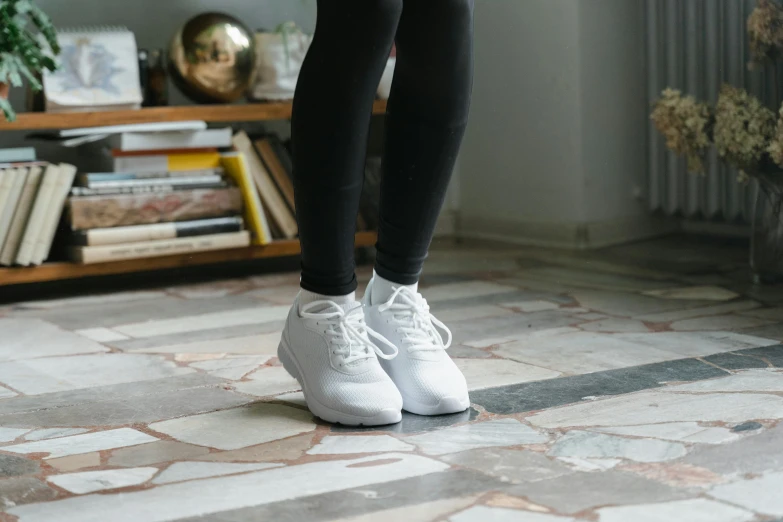a woman standing on top of a tiled floor, pexels contest winner, arabesque, wearing white sneakers, tights, at home, white uniform