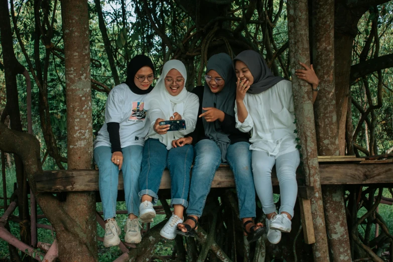 a group of women sitting on top of a tree, pexels contest winner, sumatraism, white hijab, in a tree house, avatar image, wearing casual clothing