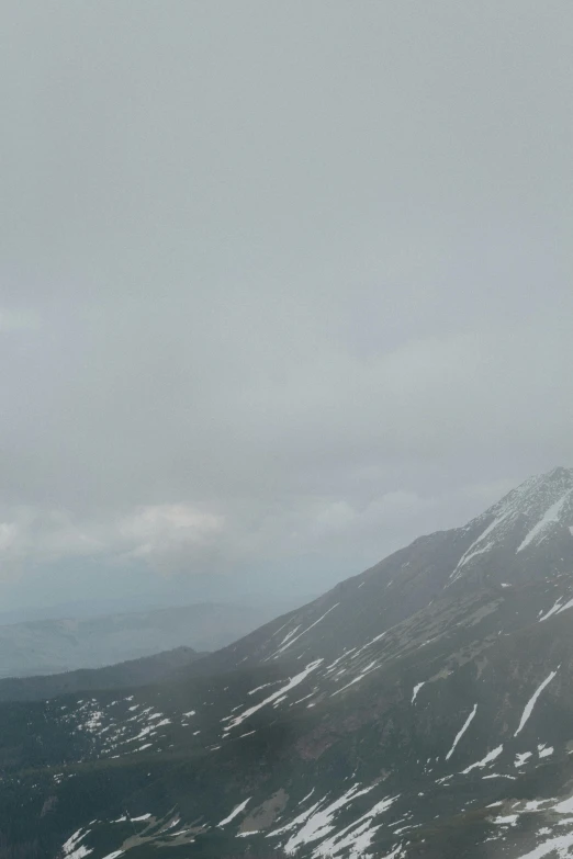 a man standing on top of a snow covered mountain, by Muggur, hurufiyya, overcast!!!, panoramic, july 2 0 1 1, foggy!