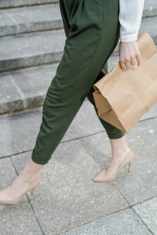 a woman walking down some steps carrying a bag, trending on pexels, renaissance, olive green slacks, on paper, detail shot, khakis