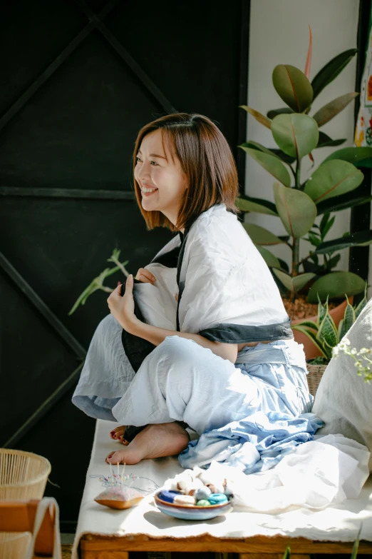 a woman sitting on a bench next to a potted plant, inspired by Cui Bai, unsplash, happening, wearing a baggy pajamas, taiwan, sitting on a sofa, profile image