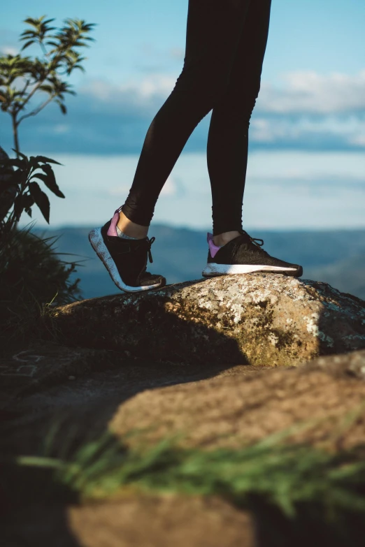 a person standing on top of a rock, running shoes, manuka, sleek legs, profile image