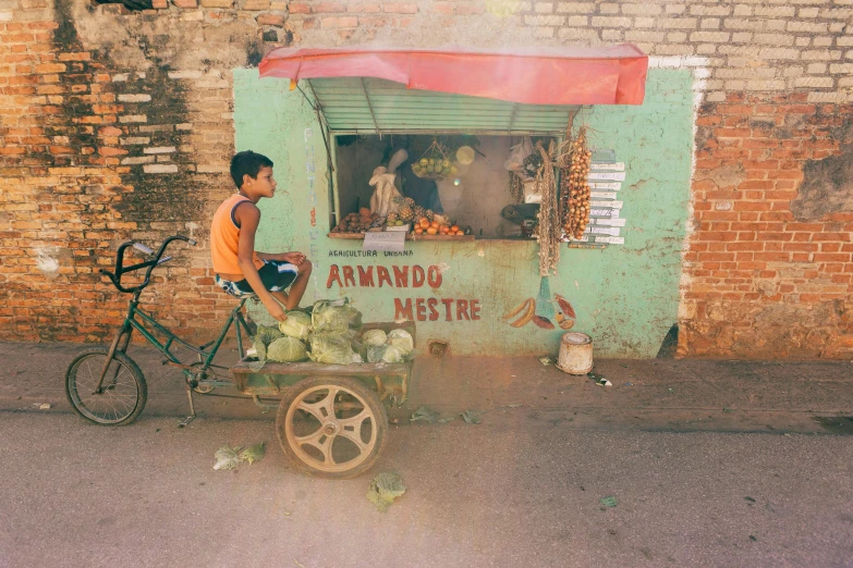 a man sitting on top of a cart filled with watermelons, an album cover, by Elsa Bleda, pexels contest winner, streets of salvador, little boy, sunfaded, with street food stalls