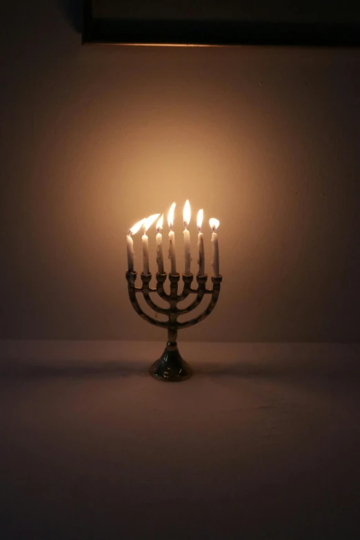 a group of lit candles sitting on top of a table, hebrew, on a gray background, unedited, multiple stories