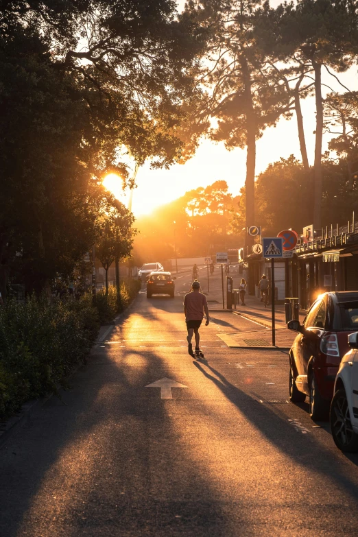 a person walking down a street next to parked cars, by Jan Tengnagel, unsplash contest winner, golden hour sunlight, abel tasman, seaside, garden road