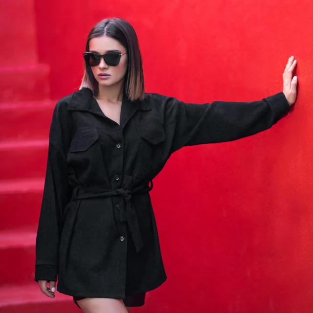 a woman standing in front of a red wall, inspired by Elsa Bleda, pexels contest winner, bauhaus, black robe, with sunglass, lucy hale, dilraba dilmurat