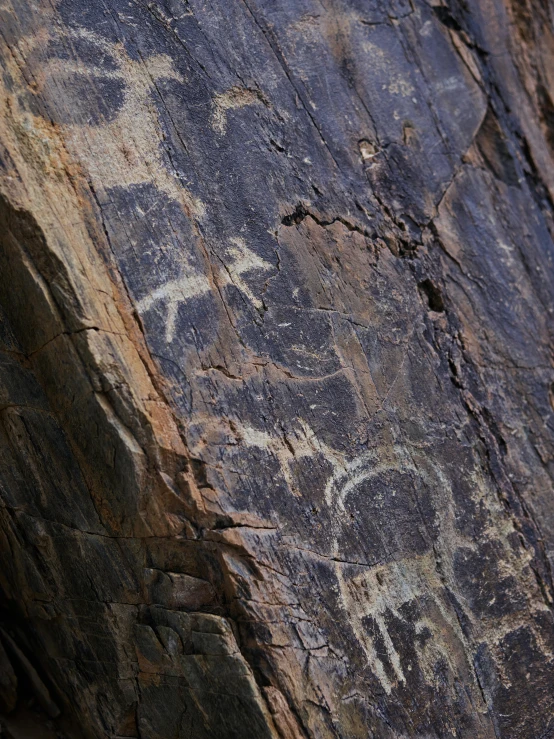 a close up of a rock with writing on it, a cave painting, pexels contest winner, distant hooded figures, oman, panel of black, ((rocks))