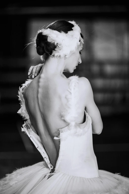 a black and white photo of a woman in a tutu, inspired by Lillian Bassman, pexels contest winner, baroque, swans, showing her shoulder from back, flapper, dressed in white