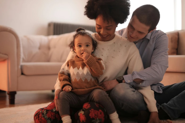 a woman and two children sitting on the floor, pexels, brown clothes, father with child, sitting on the couch, mixed race