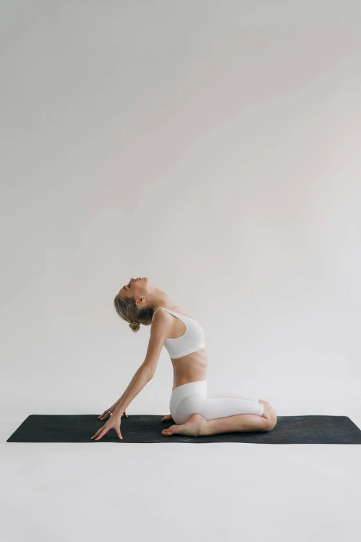 a woman doing a yoga pose on a yoga mat, by Rachel Reckitt, light and space, sleek white, low quality photo, ultrawide image, dwell