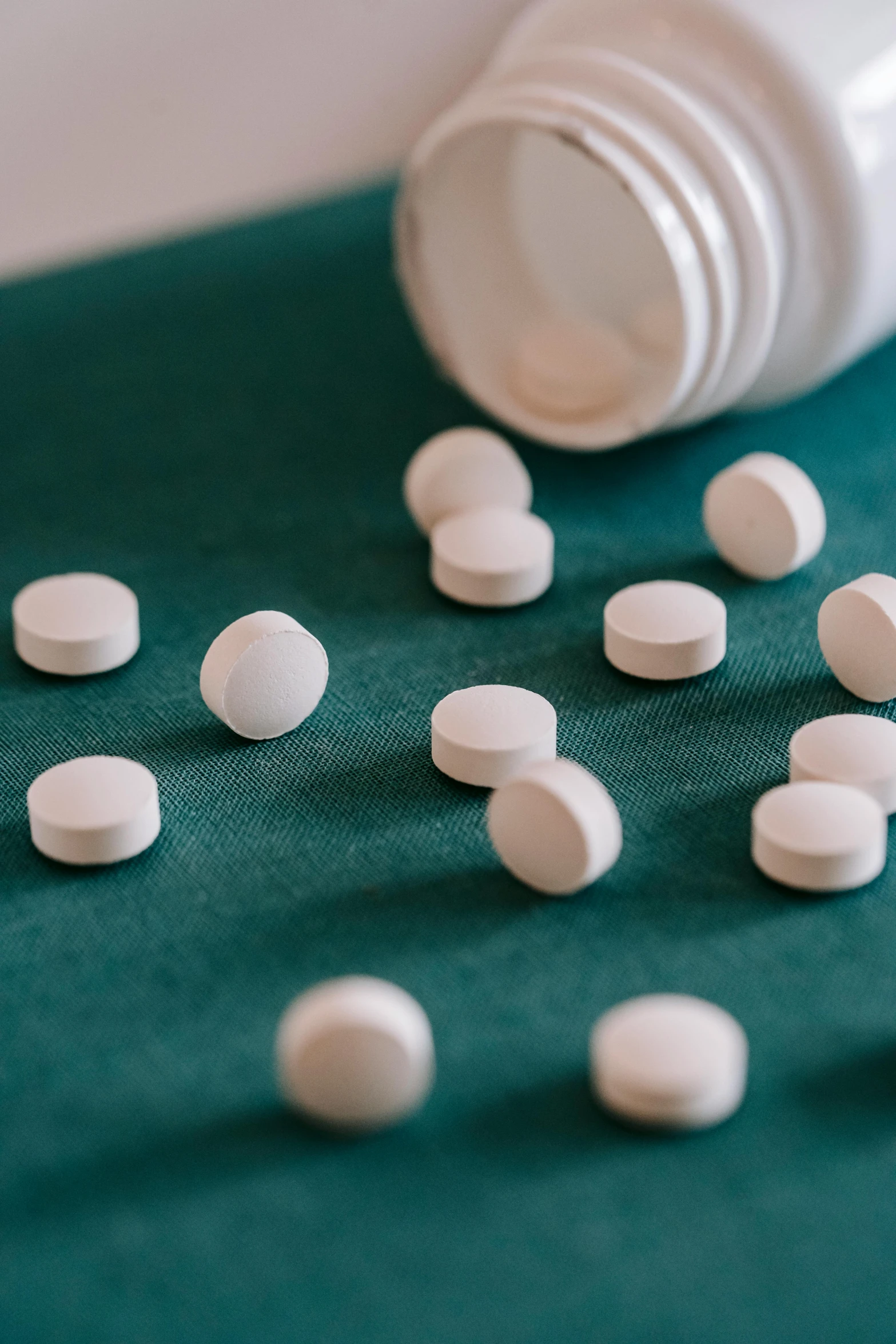 a close up of a bottle of pills on a table, unsplash, antipodeans, sea - green and white clothes, paul barson, multiple stories, round-cropped