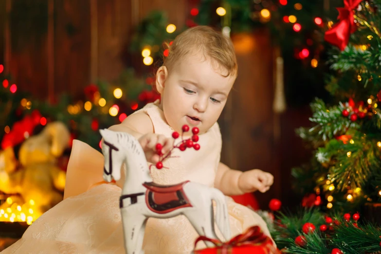 a baby playing with a toy horse in front of a christmas tree, by Emma Andijewska, shutterstock, fine art, 15081959 21121991 01012000 4k, candy decorations, thumbnail, a wooden