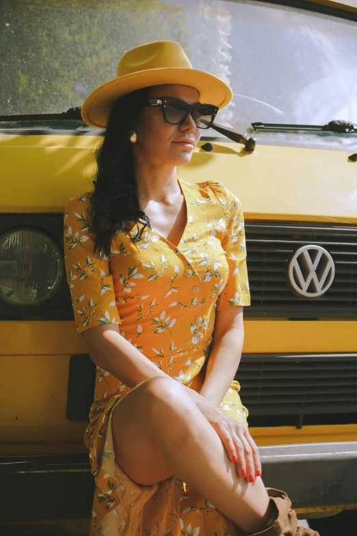 a woman sitting on the side of a yellow van, inspired by Wes Anderson, unsplash, renaissance, wearing in a summer dress, kombi, wearing sunglasses and a hat, square