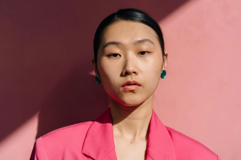 a woman standing in front of a pink wall, inspired by Russell Dongjun Lu, trending on pexels, hyperrealism, an earring, teal suit, ethnicity : japanese, demna gvasalia