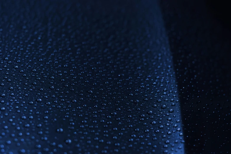 a close up of water droplets on a blue cloth, by Thomas Häfner, unsplash, dark blue leather armor, vinyl material, ultradetailed, midnight-blue