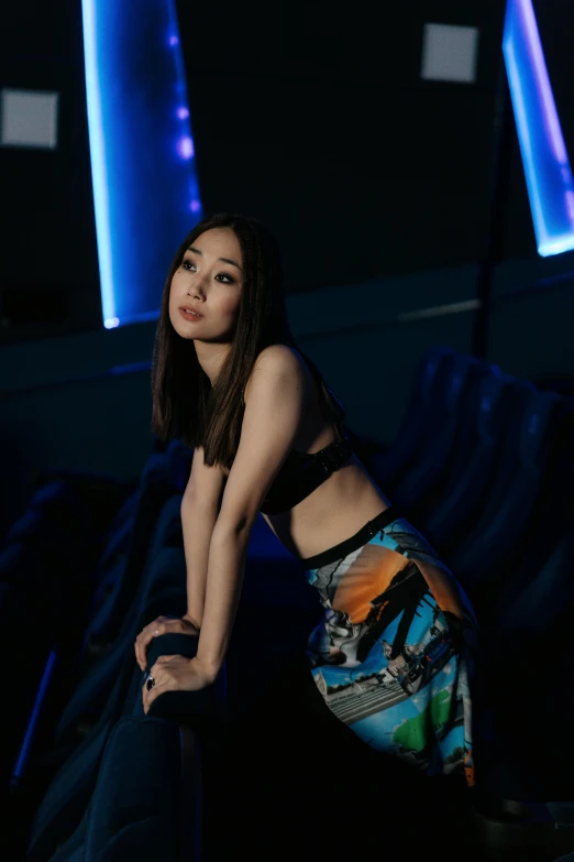a woman sitting on a chair in a dark room, an album cover, inspired by Feng Zhu, holography, midriff, standing in a starbase bar, high quality photo, gongbi