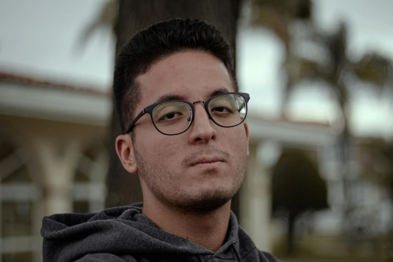 a close up of a person wearing glasses, by Alejandro Obregón, reddit, casual pose, full frame image, student, sam nassour