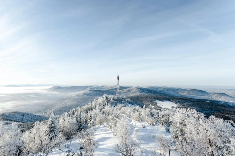 a person standing on top of a snow covered mountain, by Thomas Häfner, unsplash contest winner, bauhaus, lead - covered spire, lower saxony, velly distant forest, polsat