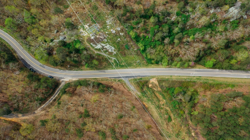 an aerial view of a winding road in the mountains, by Dan Frazier, mixed art, an abandoned, thumbnail, high quality image”