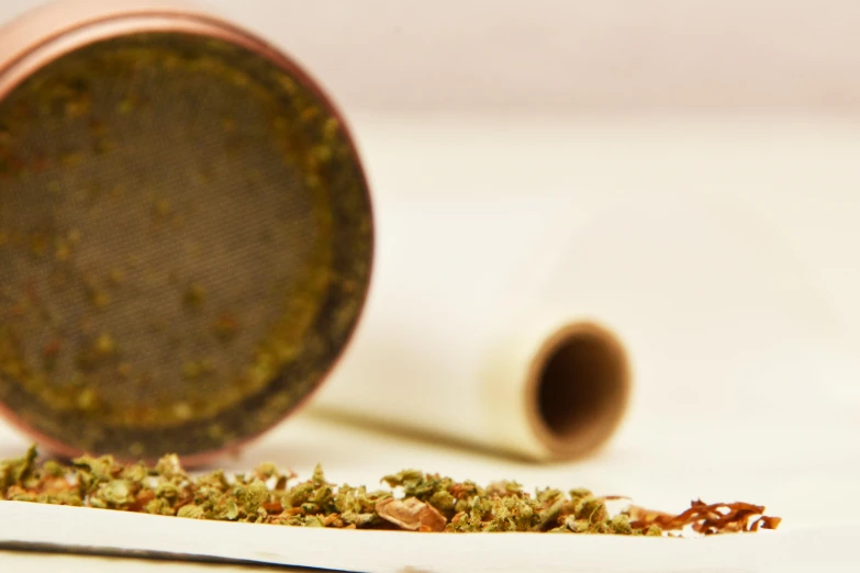 a cup sitting on top of a table next to a roll of paper, inspired by Mary Jane Begin, renaissance, spices, mid closeup, pipe, a green