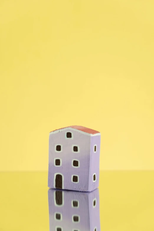 a toy house sitting on top of a table, a picture, inspired by Clarice Beckett, unsplash, folk art, yellow purple, square, ceramic, tall