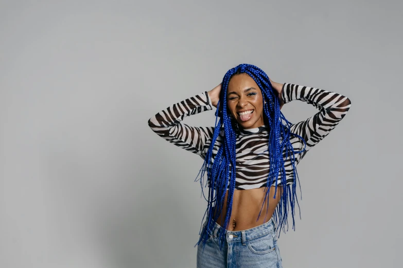 a woman with blue dreadlocks posing for a picture, trending on pexels, wearing a cropped tops, she is smiling and excited, in front of white back drop, blue and black scheme