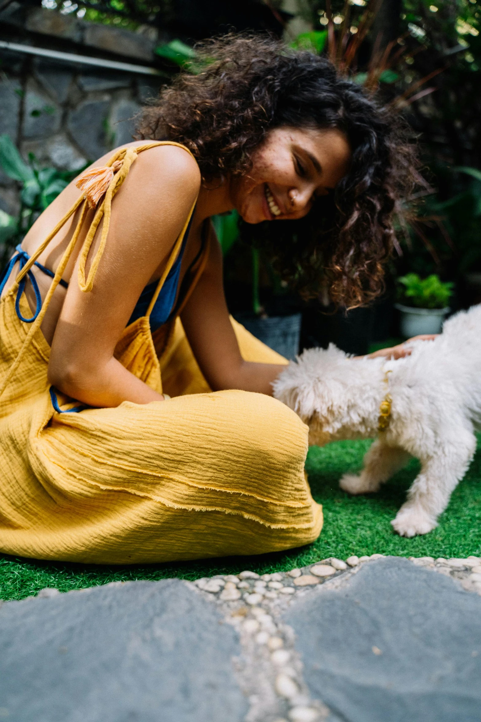 a woman in a yellow dress petting a white dog, pexels contest winner, sustainable materials, lawn, bali, medium detail