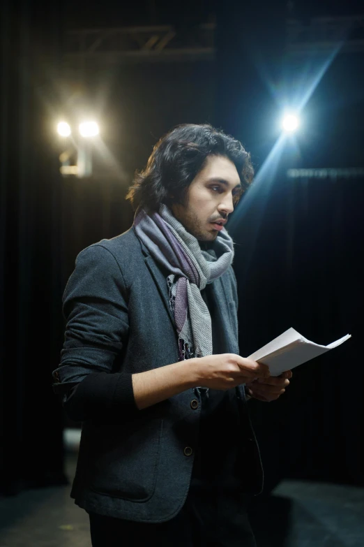 a man reading a book in a dark room, a portrait, shutterstock, performing on stage, looking serious, ( ( theatrical ) ), riyahd cassiem