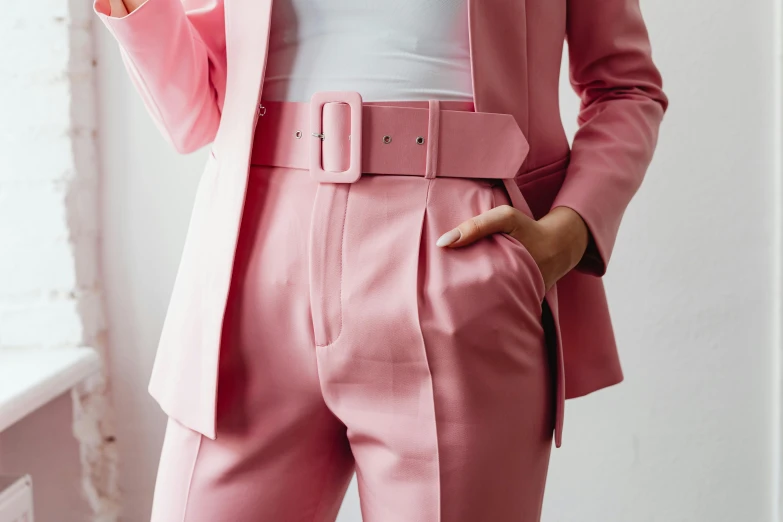 a woman in a pink suit holding a cell phone, by Emma Andijewska, trending on pexels, wide belt, wearing pants, bottom body close up, an elf in a suit