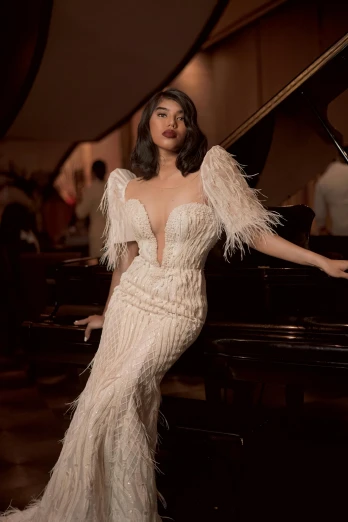a woman posing next to a grand piano, inspired by Ramon Pichot, happening, white regal gown, detailed feathers, zendaya, met collection