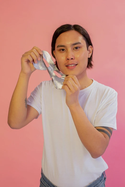 a man putting on a tie in front of a pink wall, an album cover, inspired by Russell Dongjun Lu, pexels contest winner, holding a rainbow tiger gem, wearing translucent sheet, nonbinary model, holding a white duck