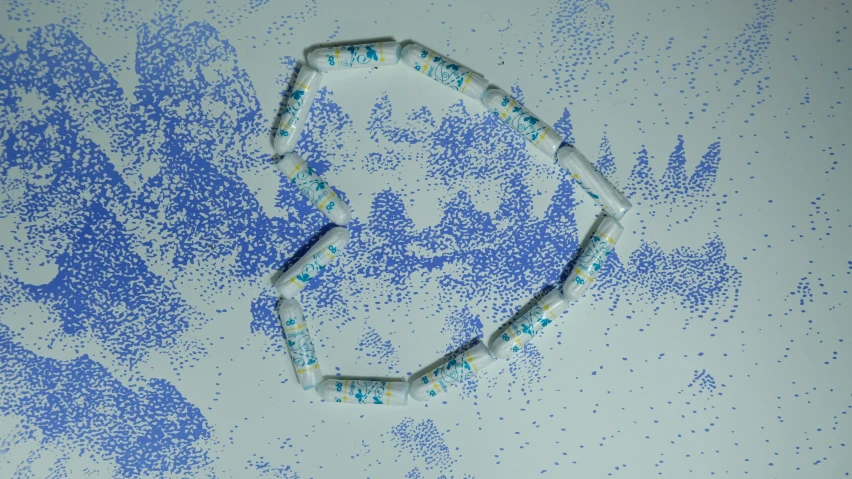 a close up of a bracelet on a table, an album cover, inspired by Howardena Pindell, kinetic pointillism, blue - print, rna bioweapon, computer generated, syringe