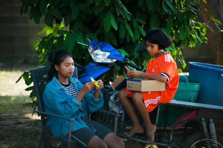 a woman sitting next to a child on a scooter, pexels contest winner, village girl reading a book, cardistry, square, thawan duchanee