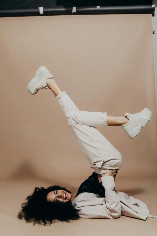 a woman doing a handstand in a studio, an album cover, trending on pexels, sneaker photo, white puffy outfit, laying down, satisfied pose