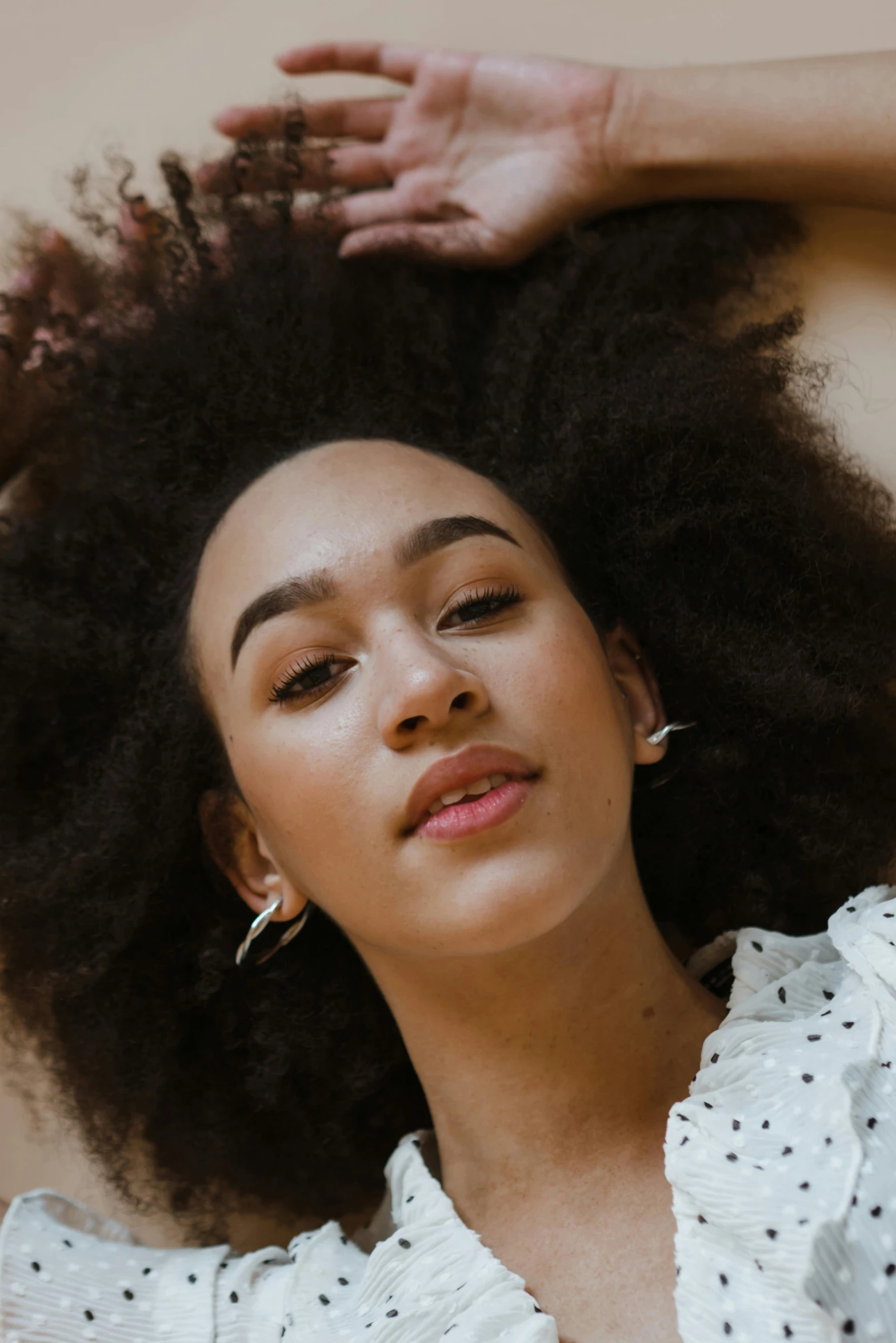 a woman with an afro is posing for a picture, trending on pexels, portrait sophie mudd, top down angle, her hair pinned up, editorial image