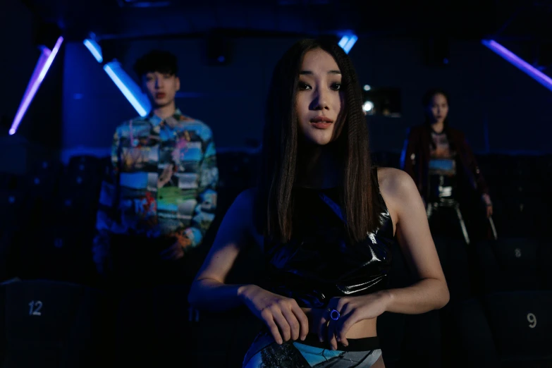 a group of people standing next to each other in a dark room, an album cover, inspired by Wang E, pexels contest winner, wearing a crop top, with glowing blue lights, xue han, wearing futuristic clothing