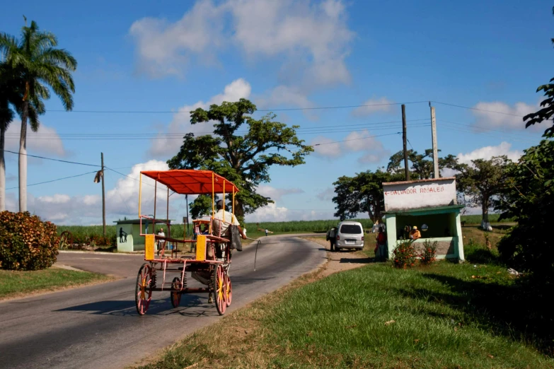 a man riding a horse drawn carriage down a road, colors of jamaica, slide show, avatar image