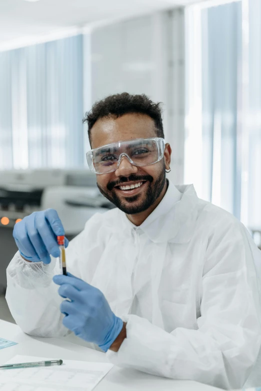 a man in a lab coat and goggles holding a test tube, pexels contest winner, brown skin man with a giant grin, arab, thumbnail, plating