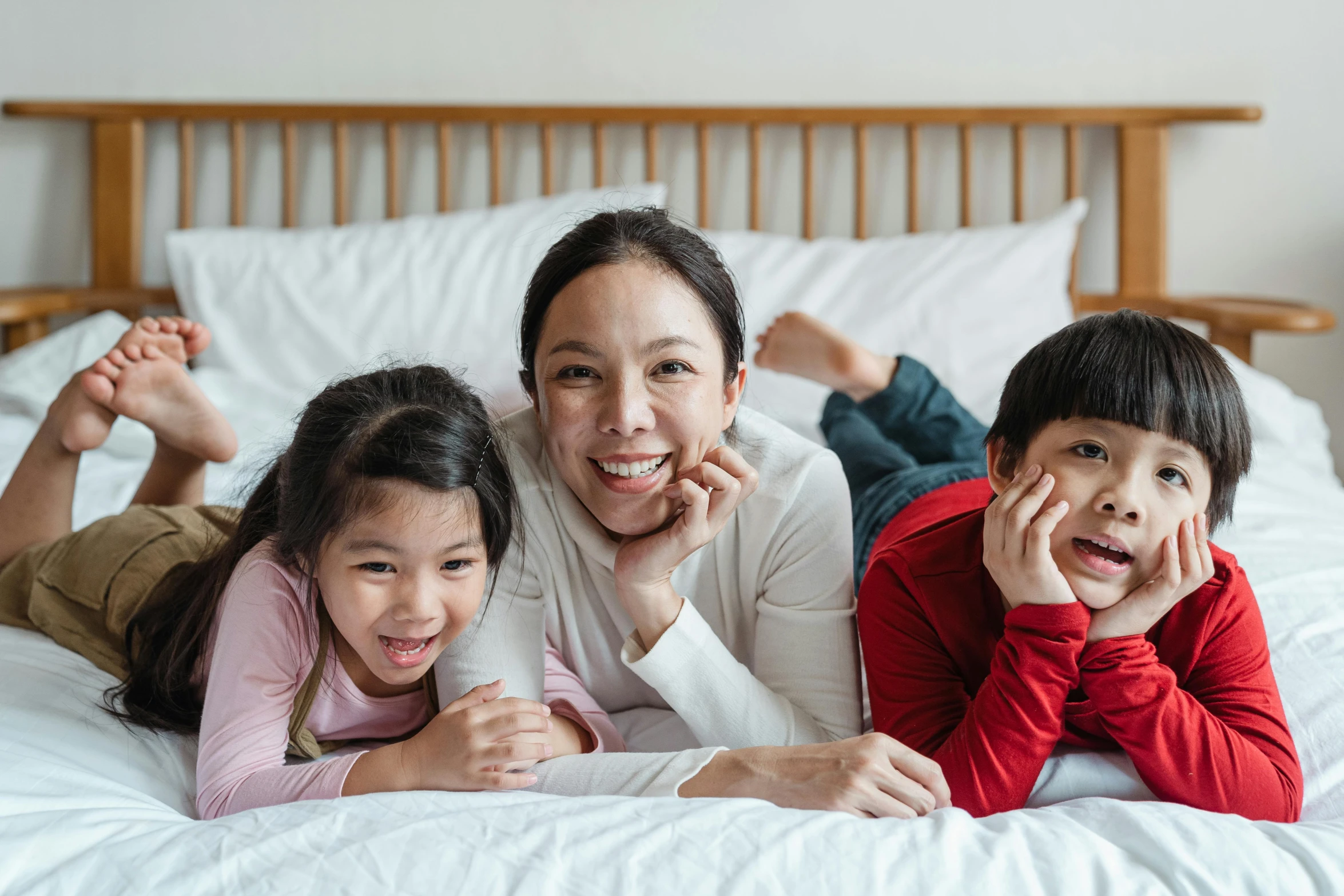 a woman and two children laying on a bed, a cartoon, pexels contest winner, asian origin, movies, manuka, smiling for the camera