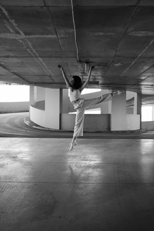 a person doing a trick on a skateboard in a parking garage, a black and white photo, inspired by Elizabeth Polunin, arabesque, pose(arms up + happy), nanae kawahara, square, bridge