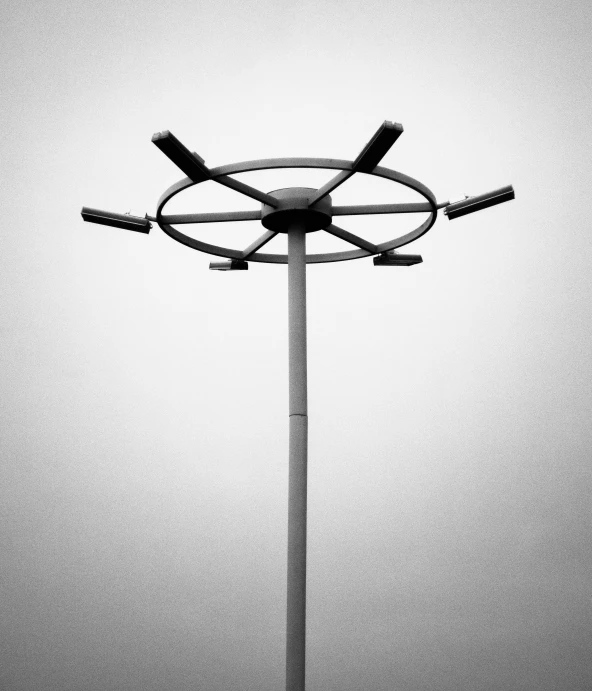 a black and white photo of a street light, an abstract sculpture, by Matthias Weischer, postminimalism, ( ferris wheel ), grey sky, six arms, symmetrical!! sci-fi