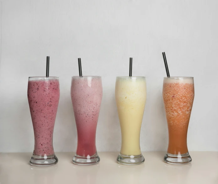 a row of four drinks sitting next to each other, milkshake, 4 colors, high quality product image”, light toned