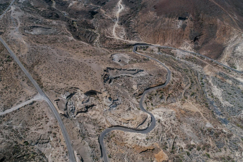 an aerial view of a winding road in the desert, by Lee Loughridge, les nabis, landslides, paved, slate, black