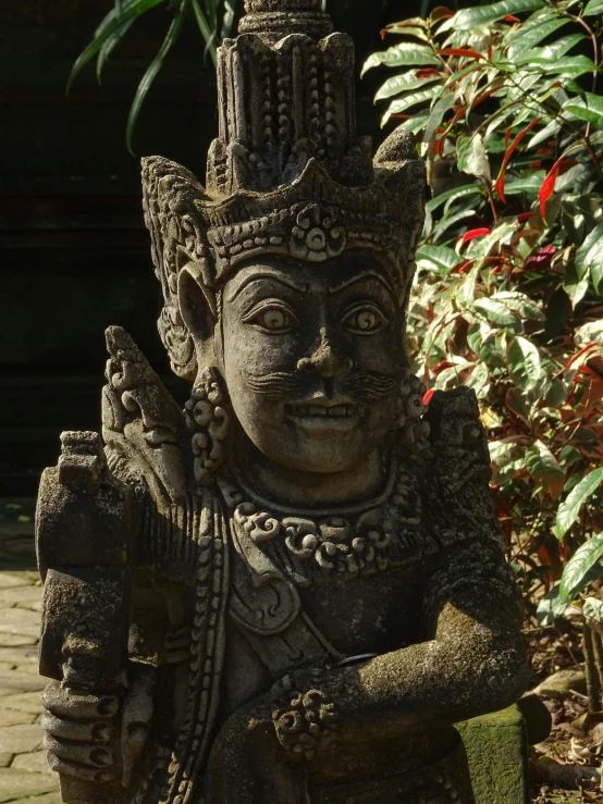 a statue sitting in the middle of a garden, inspired by I Ketut Soki, smirking, very detailed”, puṣkaracūḍa, very detailed ”