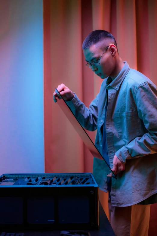 a man standing in front of a laptop computer, an album cover, by Robbie Trevino, unsplash, live performance, yanjun chengt, an instrument, tending on art station