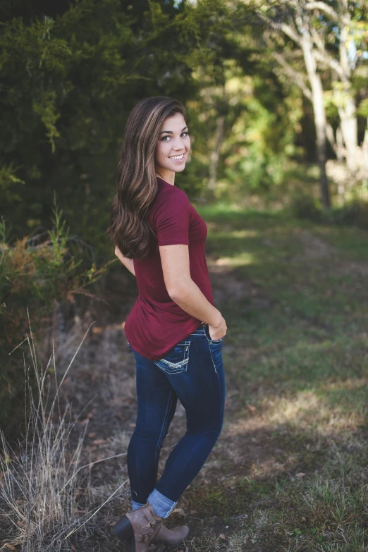a woman standing in the middle of a forest, a portrait, by McKendree Long, instagram, jeans and t shirt, long hair and red shirt, profile image, college